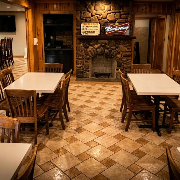 Restaurant dining room with wooden tables and chairs, a stone fireplace, and a long bar area.